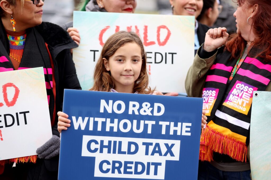 Child holding sign that says No R&D without the Child Tax Credit