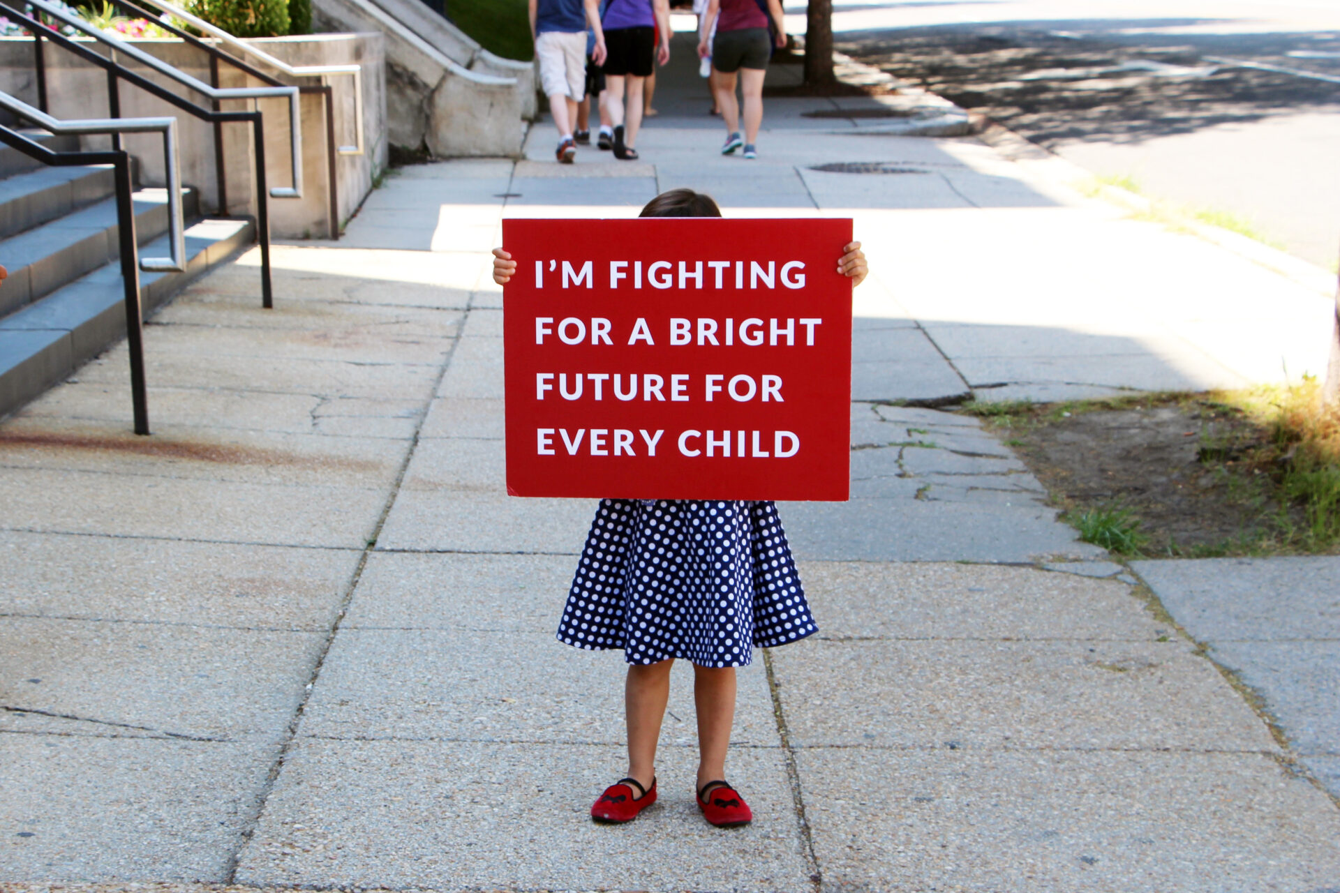 Photo of child holding a sign that says I'm fighting for a bright future for every child.
