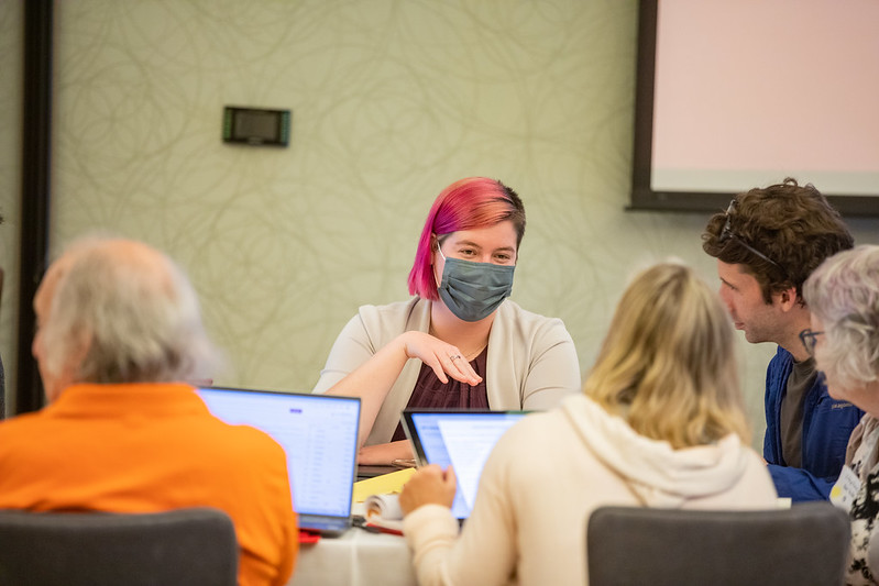A woman with pink hair and a mask sits with four RESULTS advocates, planning for Global Fund congressional advocacy visits.