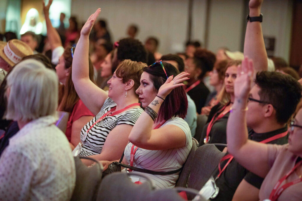 Group of attendees raise their hands at the RESULTS International conference